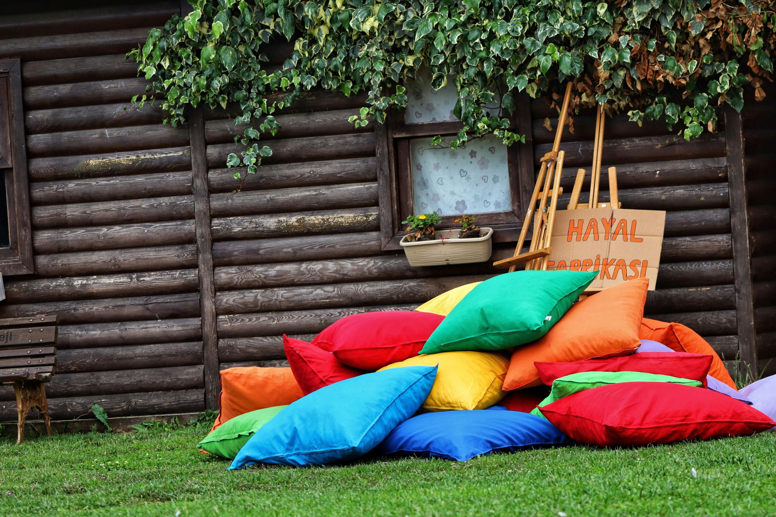 Vibrant cushions stacked outside a quaint wooden cabin, enhancing the rustic charm with colorful decor.
